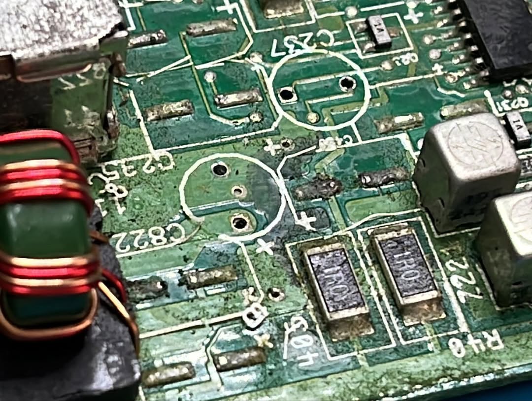 Gravi danni da elettrolita nella zona di alimentazione su Amiga 600, con piste ossidate e componenti rimossi